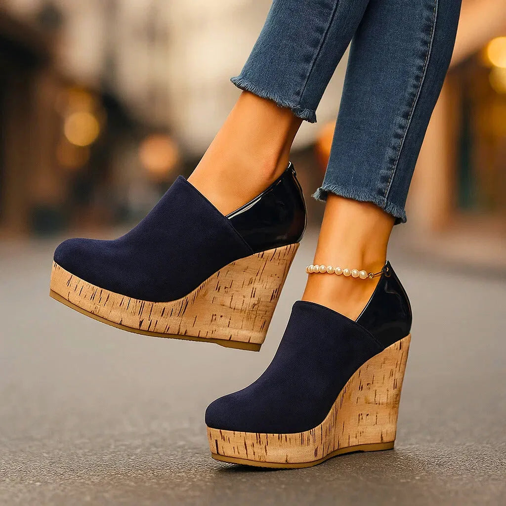 Navy suede wedge bootie shown from behind, highlighting the cork wedge heel, patent back panel and gold zip pull