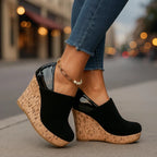 Black suede wedge ankle boot paired with cropped jeans, showing the cork platform sole and layered pearl anklet chain