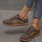 Brown and tan trainers worn on foot, side view showing contrast stripe and padded collar