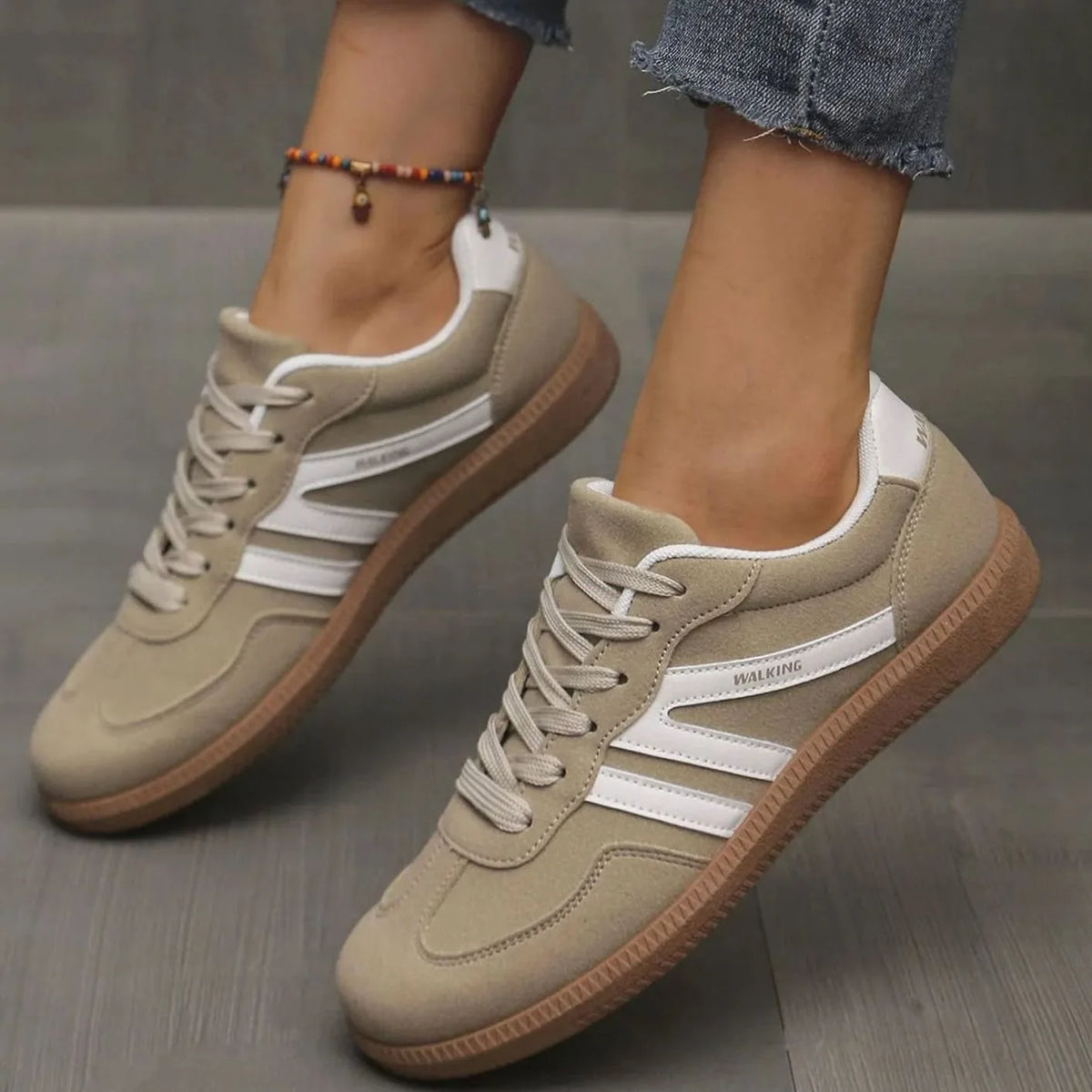 Angled view of beige trainers showing toe cap texture and layered panel construction