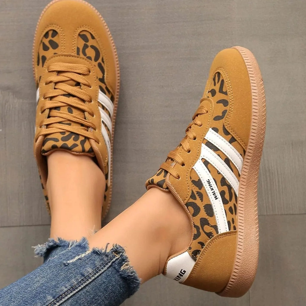 Beige trainers worn walking on textured grey flooring, showing natural movement and fit