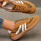 Close-up of stitched stripe panels on beige and taupe trainers with suede toe overlay