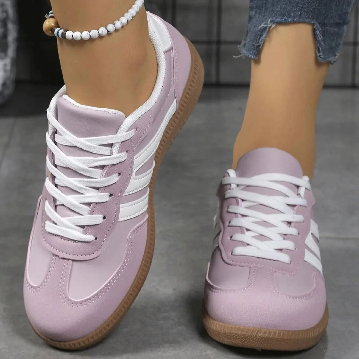 Black trainers with white stripes shown from a raised angle, focusing on the gum sole edge