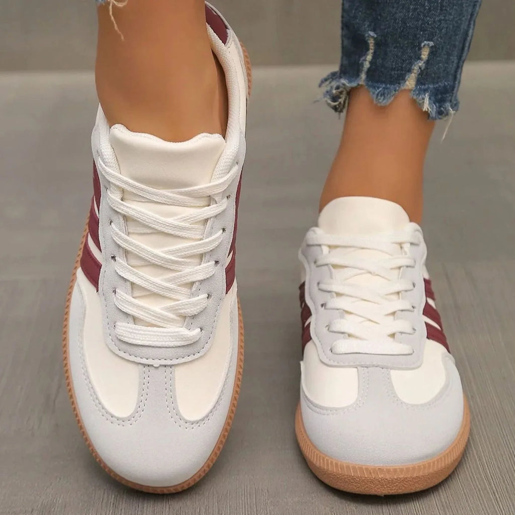 Black and white trainers paired with cropped jeans, side view on grey flooring