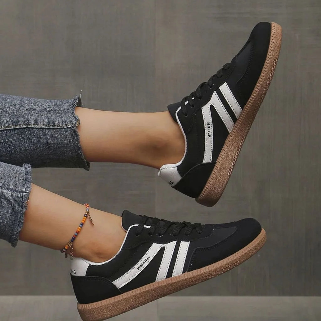 Black and white trainers worn on foot, front angle showing bold diagonal stripe detail