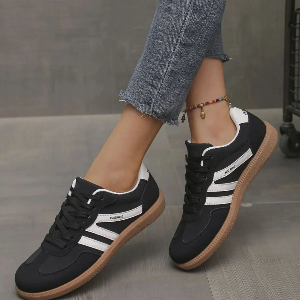 Side view of black trainers with white stripes and gum sole, foot lifted mid-stride