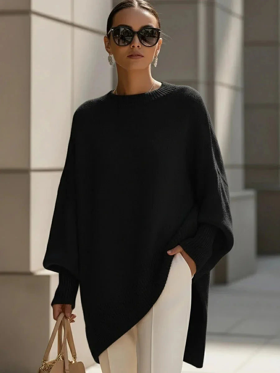 Woman wearing the oversized jumper in black with a draped asymmetric hemline falling past the hip
