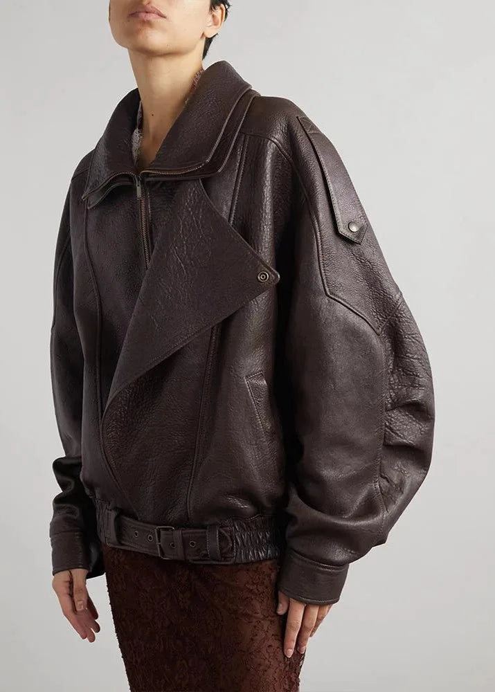 Side view of a model wearing an oversized brown leather biker jacket with wide collar and asymmetric zip