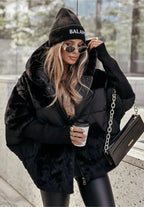 Model in a black oversized faux fur and quilted puffer coat with hood, holding a coffee cup