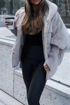 Grey oversized puffer coat with faux fur hood and ribbed cuffs, worn open over black trousers
