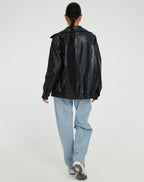 Back view of the black oversized leather jacket worn with a braided hairstyle and light denim