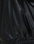 Three-quarter back view of the black leather jacket showing sleeve volume and overall relaxed silhouette