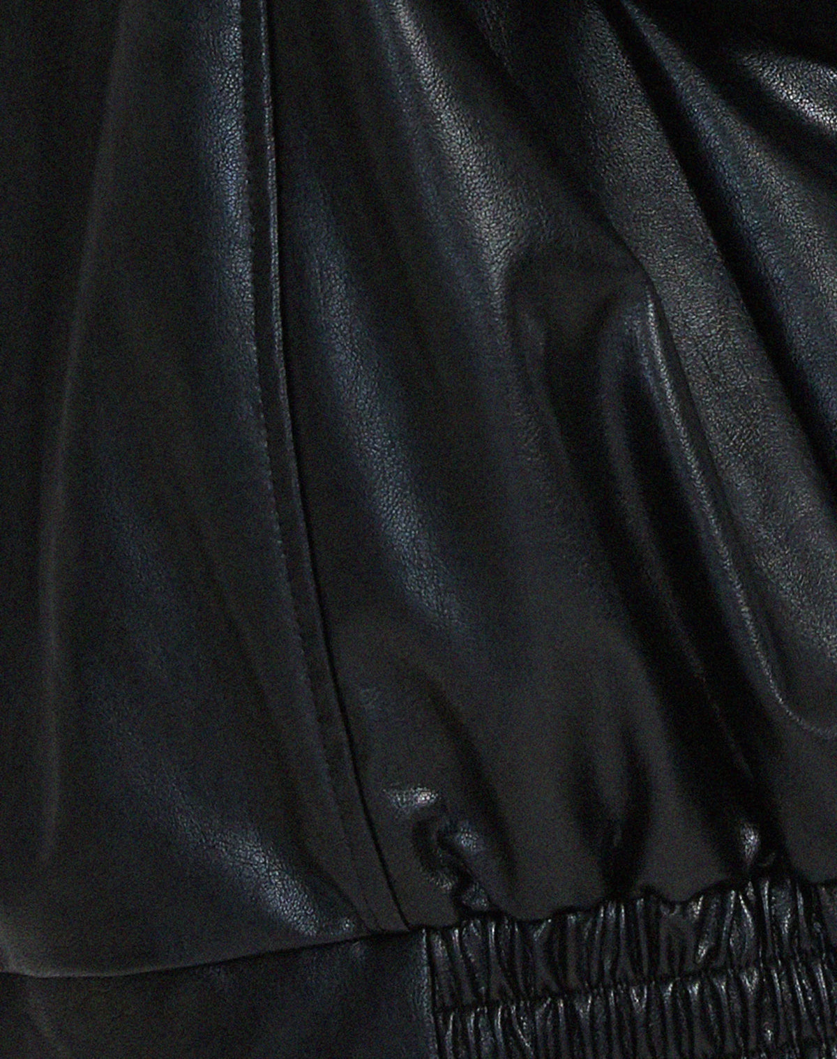 Three-quarter back view of the black leather jacket showing sleeve volume and overall relaxed silhouette