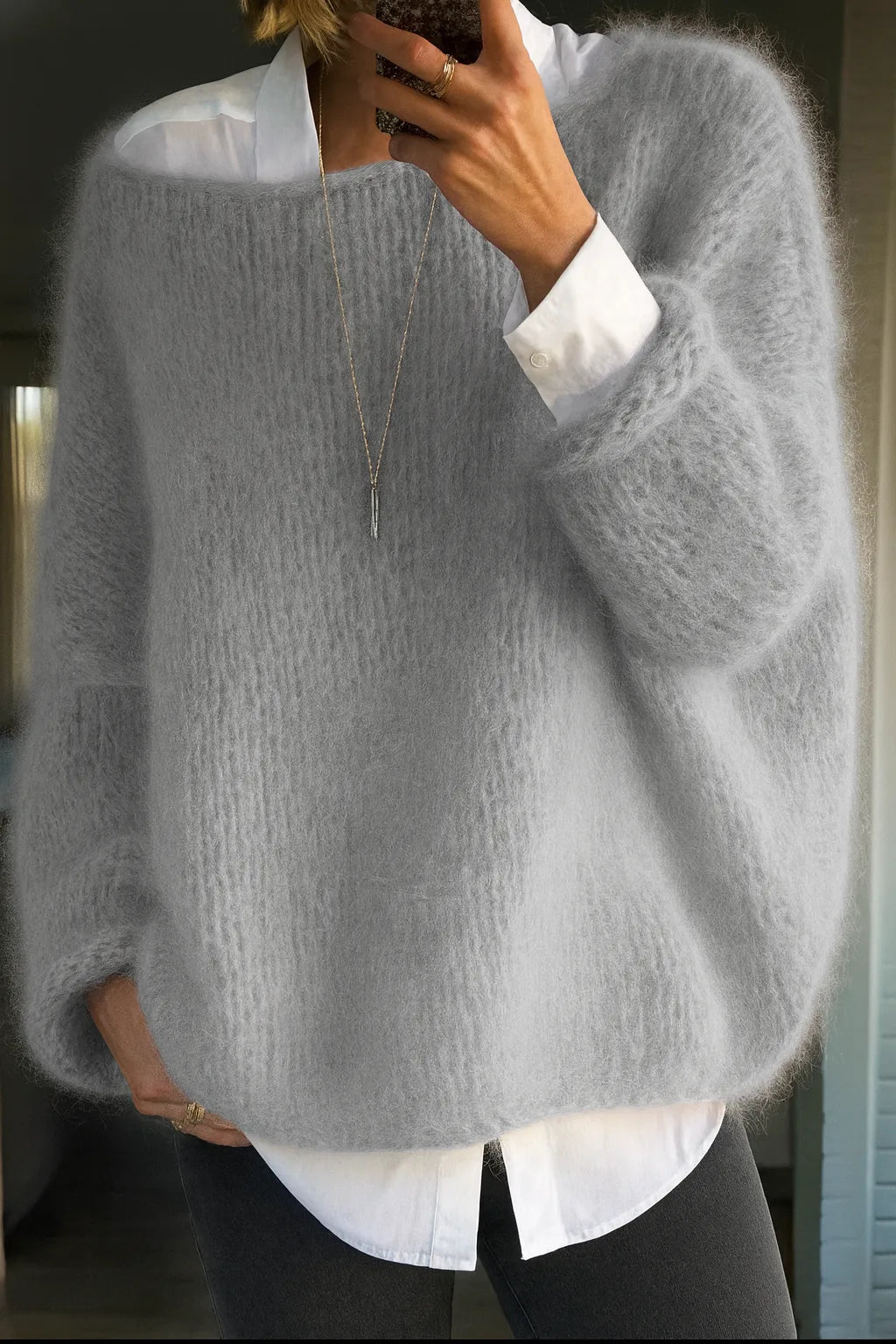 Side view of the chunky knit jumper in soft grey, worn over a crisp white collared shirt and dark trousers