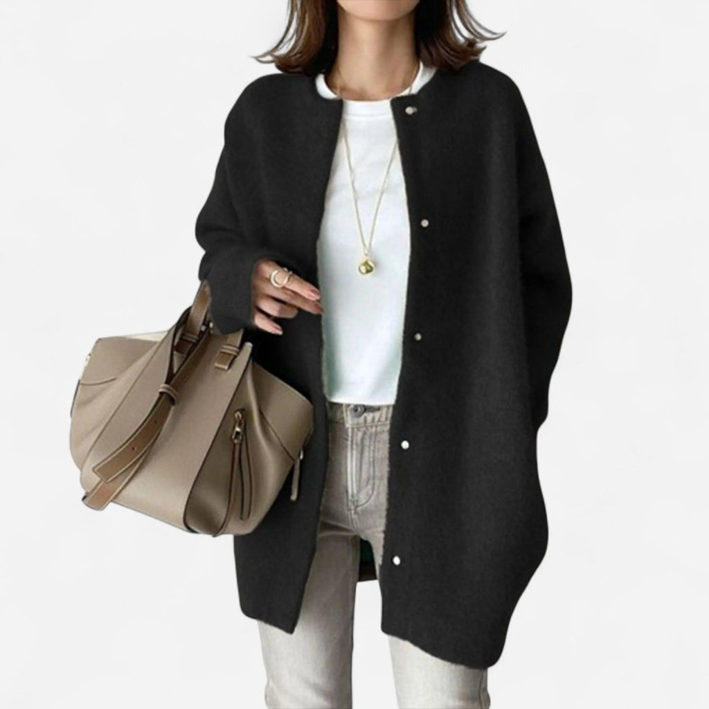 Front view of the oversized cardigan in black with round neckline and press-stud fastenings, worn open over a white top.
