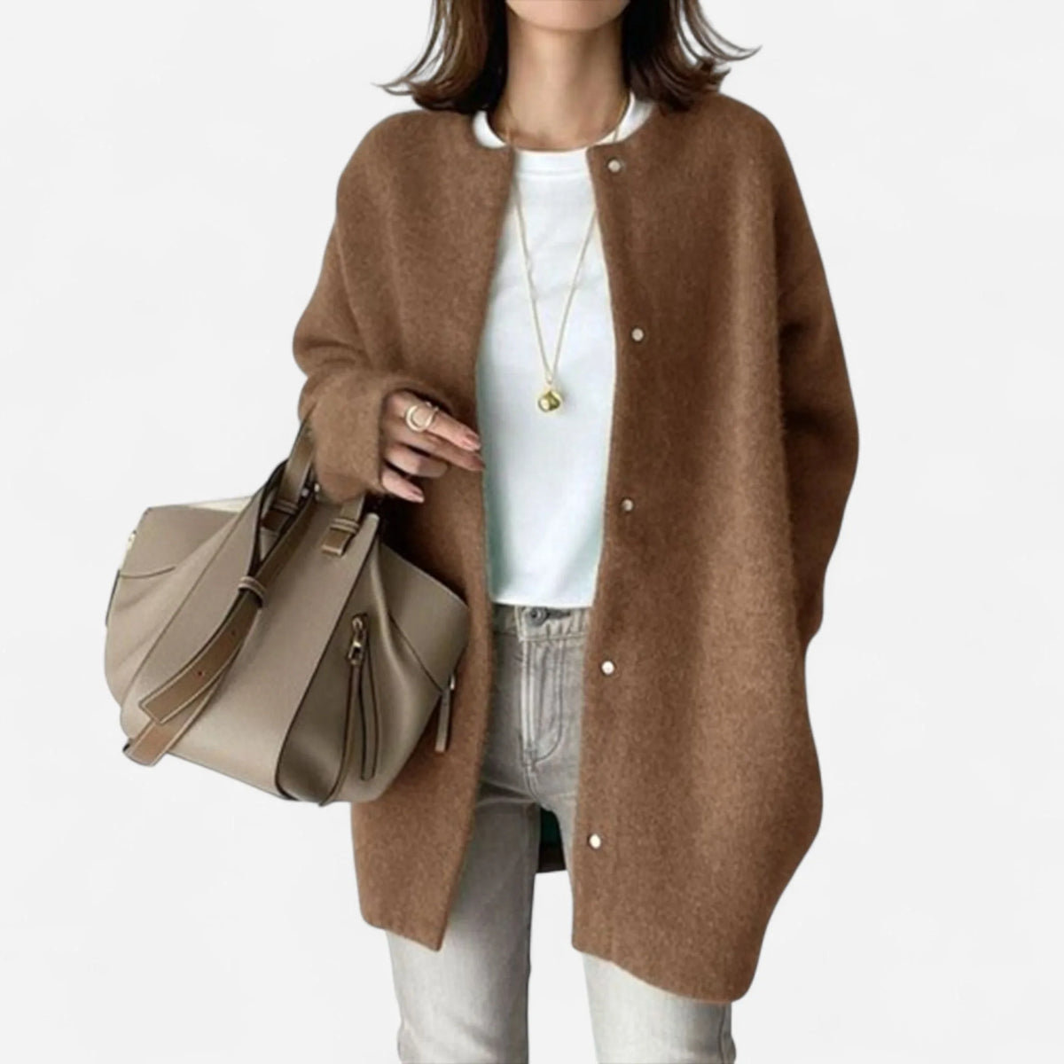 Model in a caramel brown longline knit cardigan with dropped shoulders and long sleeves, paired with light denim jeans.