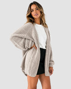 Side angle of the light beige knit cardigan showing the volume of the lantern sleeve
