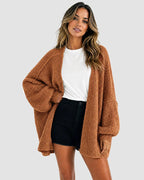 Front view of the cardigan in rust brown, styled open with a white tee and denim shorts