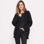 Woman wearing an oversized black ribbed cardigan buttoned over a black top and black trousers, front view