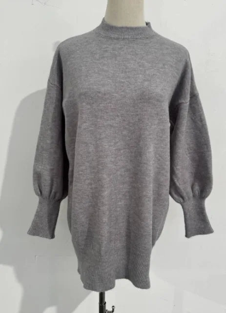 Grey oversized knit jumper shown from the front with ribbed cuffs and relaxed tunic-length hem