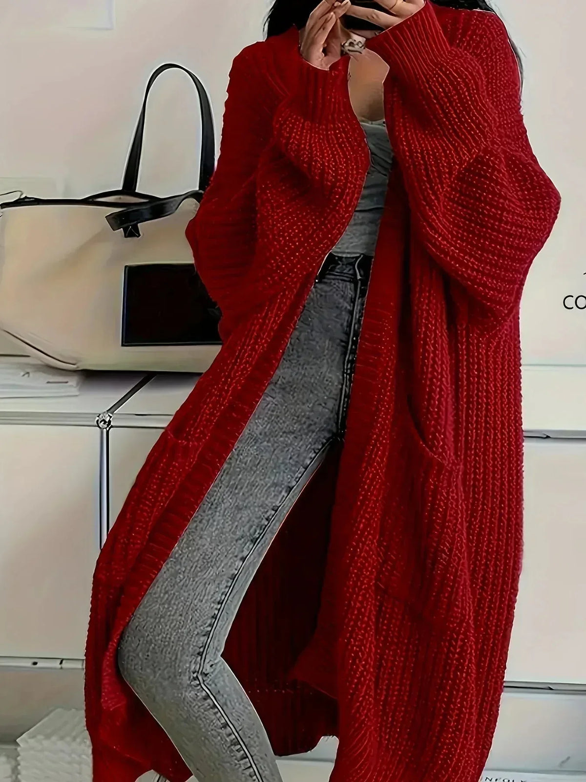 Deep red oversized cardigan in chunky rib knit, worn open over a grey top and jeans