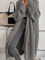 Grey oversized ribbed cardigan draping to the ankle, showing patch pockets and wide cuffed sleeves