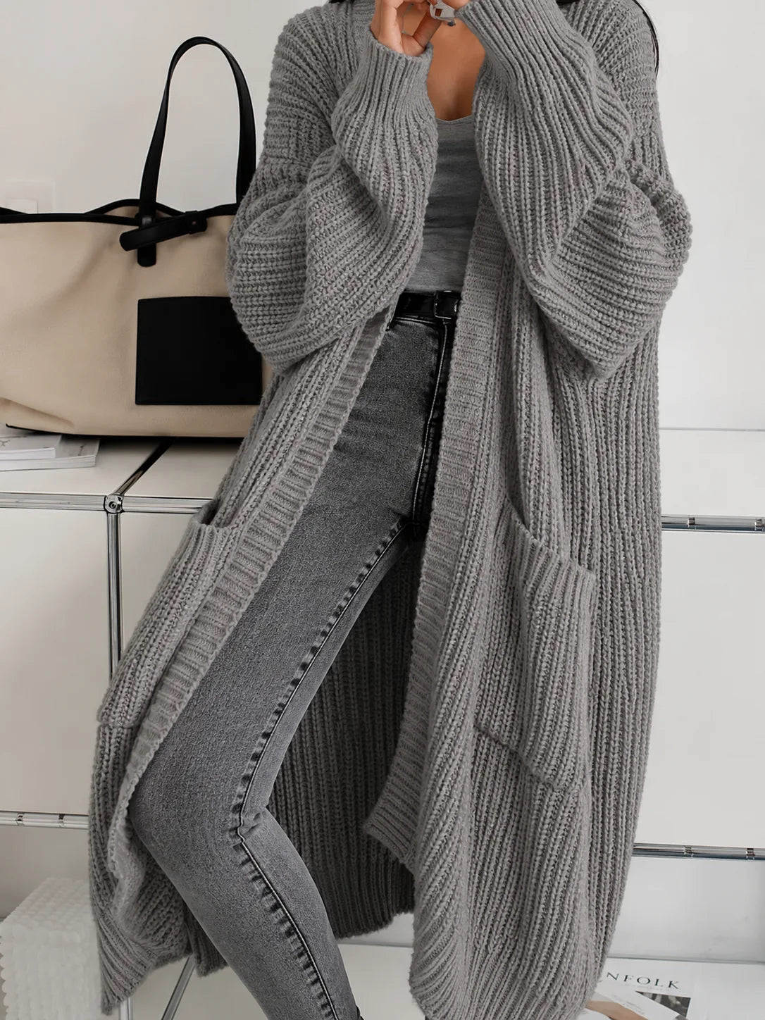 Grey oversized ribbed cardigan draping to the ankle, showing patch pockets and wide cuffed sleeves