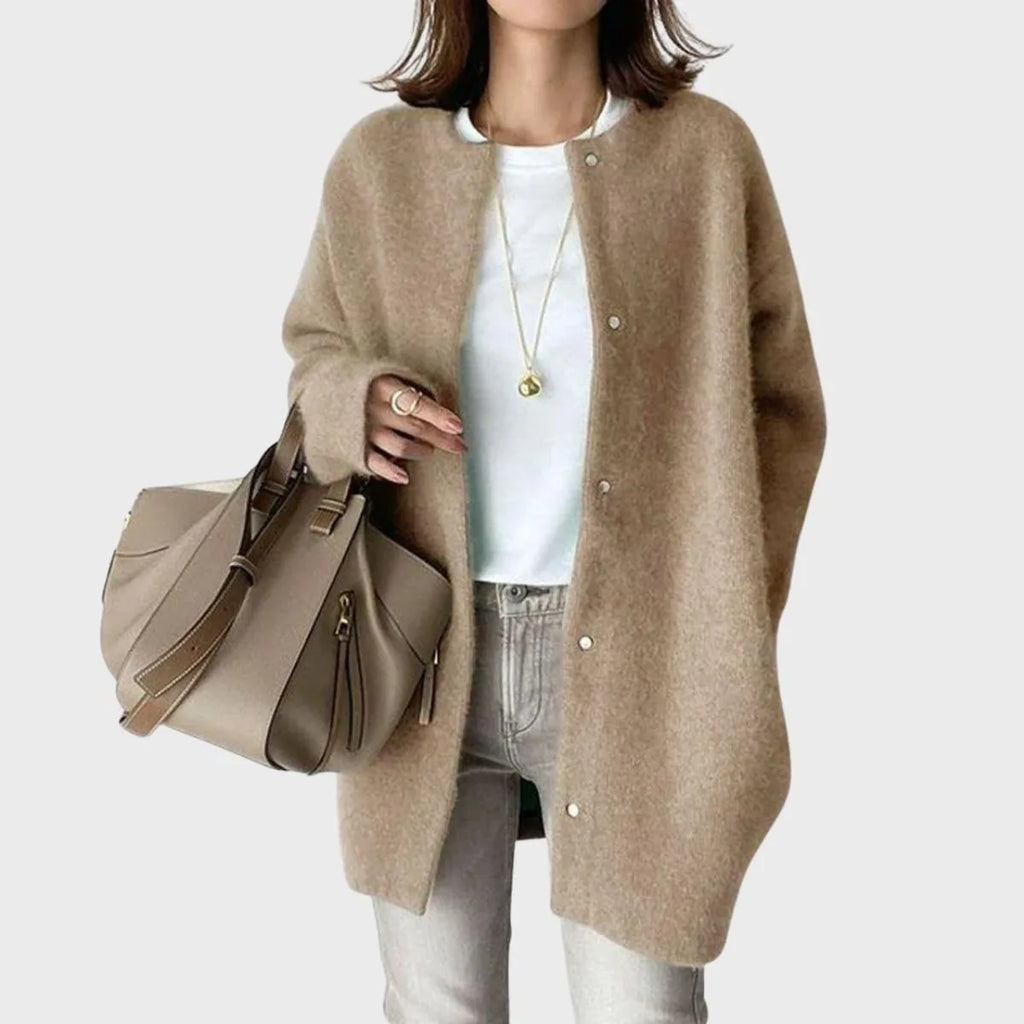 Woman in a khaki oversized snap-front cardigan carrying a taupe tote bag, long sleeves and round neckline visible
