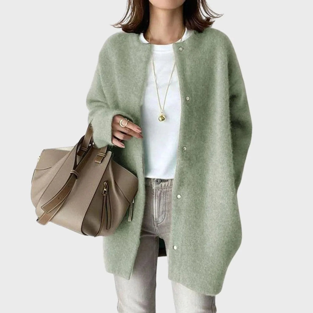 Sage green knit cardigan with round neckline and snap-front fastening, styled with a white tee and denim