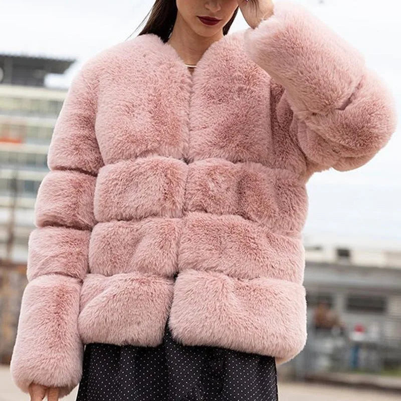 Close-up front view of a woman wearing a pink faux fur cropped puffer jacket with ribbed cuffs and stand collar