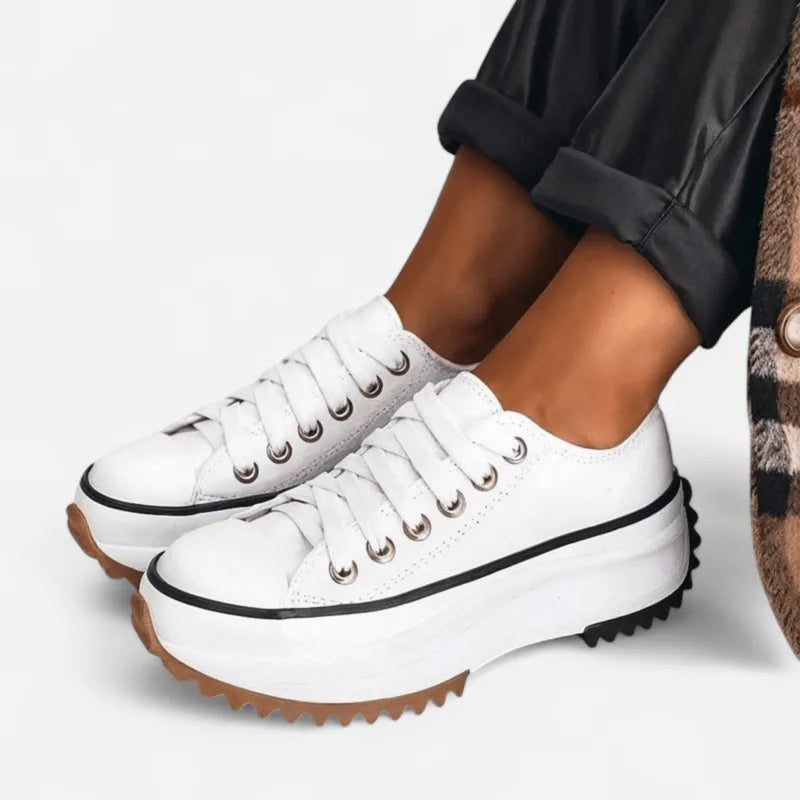 Side profile of white canvas platform trainers with silver eyelets and a thick cream tread sole