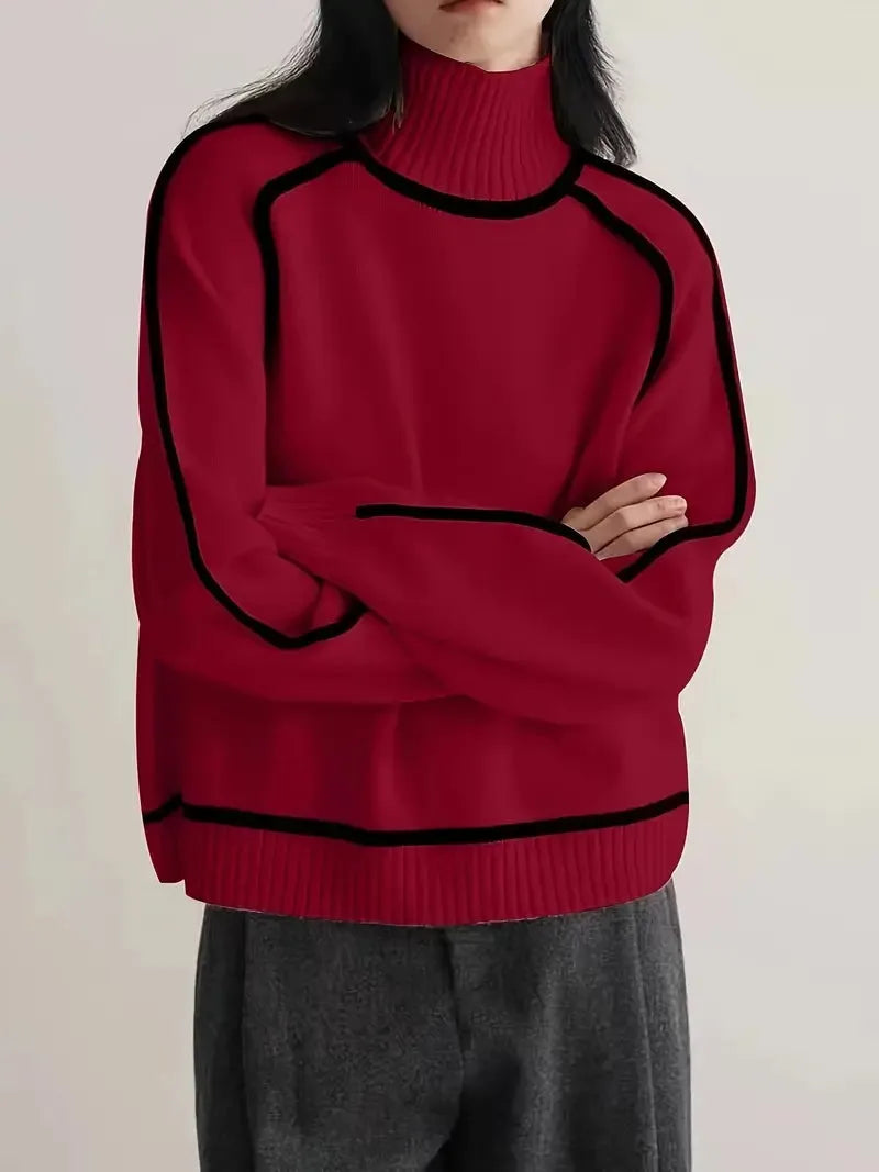 Close-up of cream knit jumper showing the ribbed turtleneck collar and black piped shoulder seam