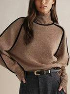 Camel brown ribbed turtleneck jumper with black piping, styled with a black belt and cream trousers
