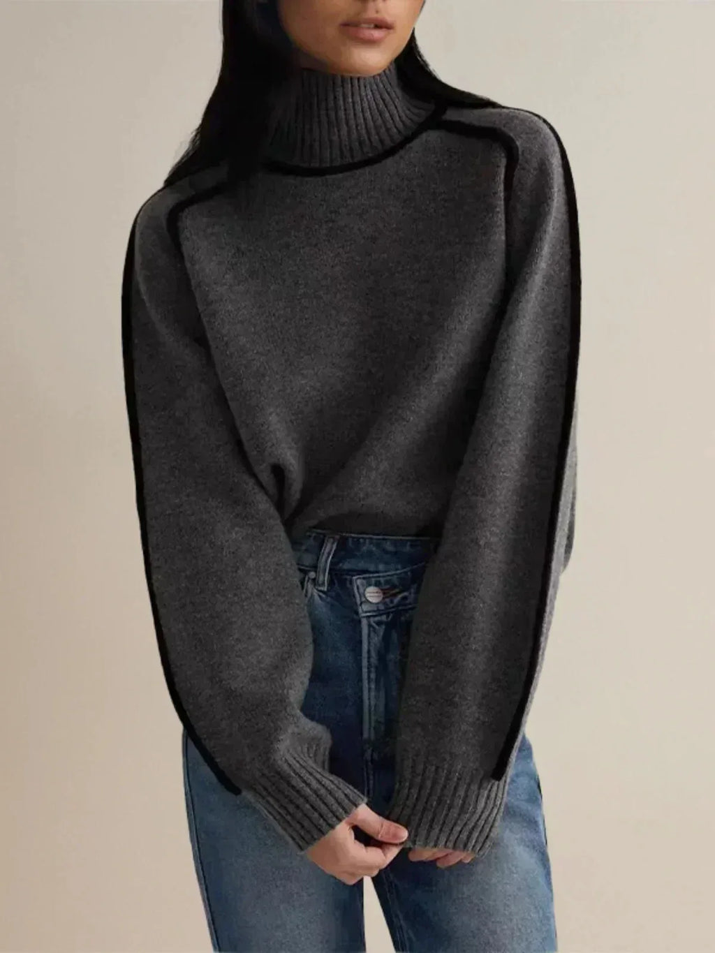 Charcoal grey turtleneck jumper with black piping worn over blue denim jeans