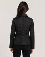 Back view of black quilted jacket showing waist tab detail and diamond-quilted panels