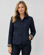 Navy quilted jacket with buttoned collar and checked cuffs, worn with dark denim jeans