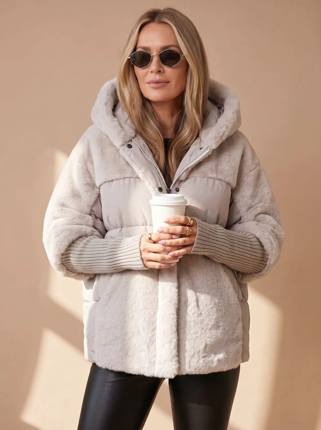 Front view of grey faux fur puffer jacket with hands in fur-trimmed side pockets, hood up