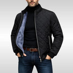 Black quilted jacket worn open over a black polo neck, showing the diamond stitch pattern and zip pocket detail