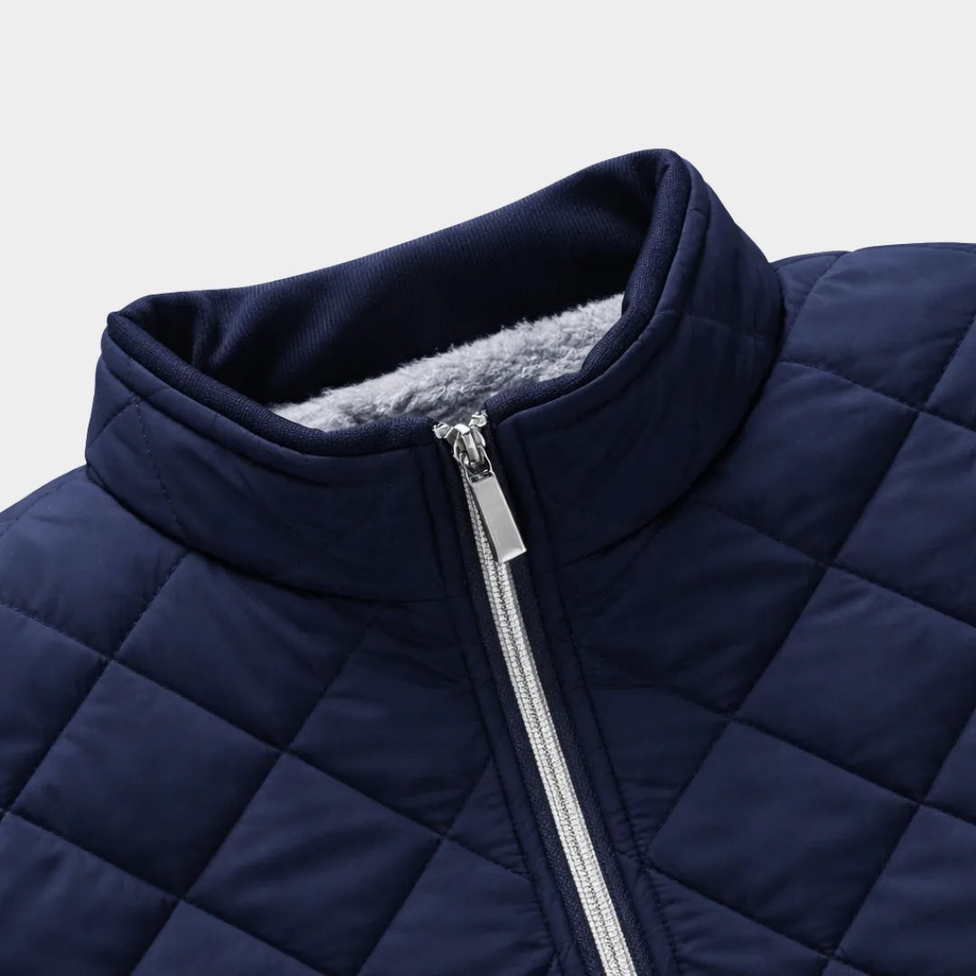 Close-up of the navy jacket's stand collar and zip pull, showing the quilted shell and fleece trim inside