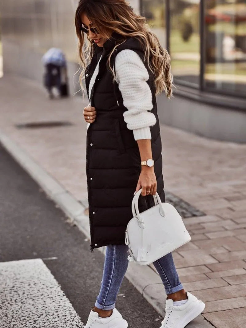 Side profile of a black longline quilted gilet showing its knee-length hem and fitted hood