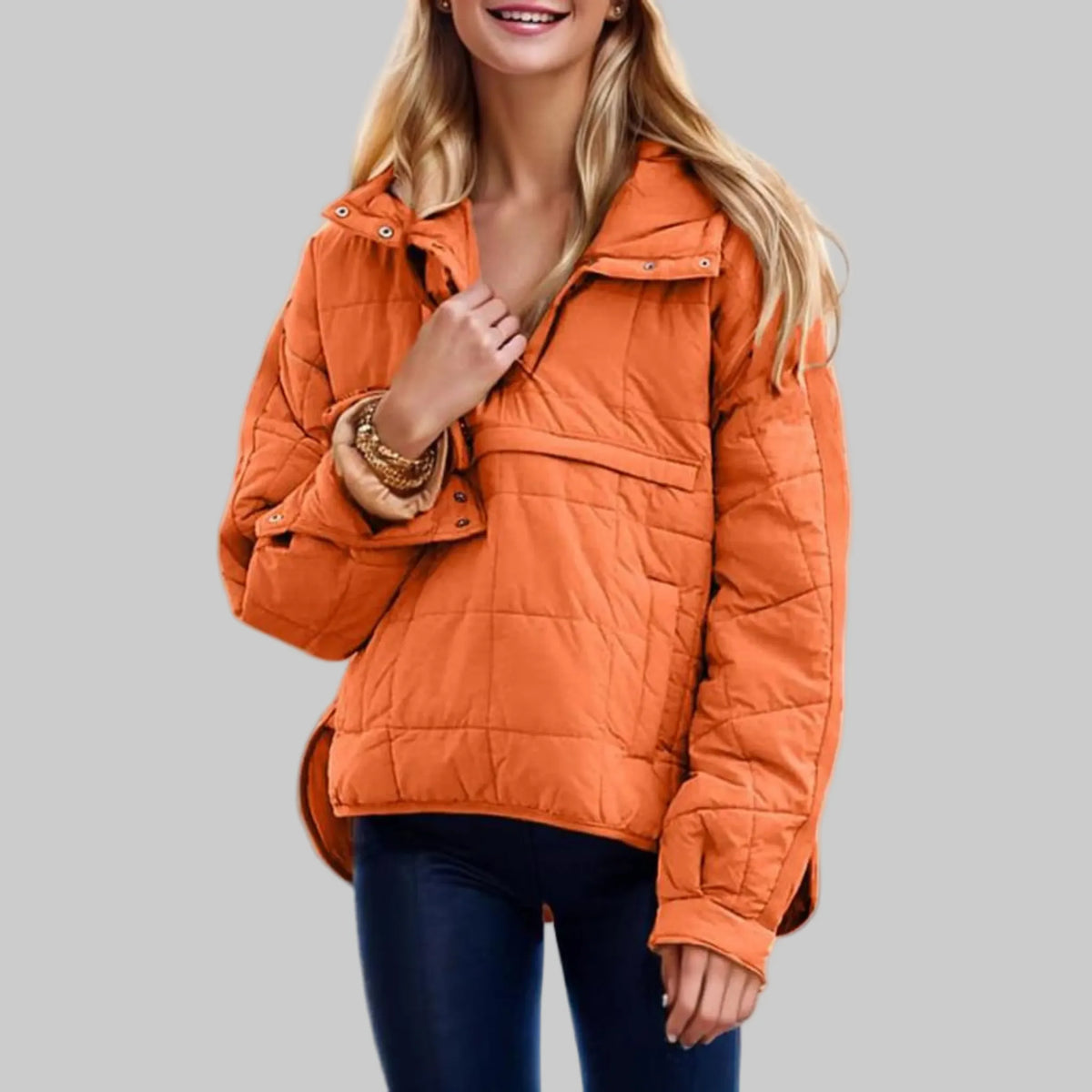 Orange quilted hooded pullover jacket with snap-button placket, worn open over jeans, front three-quarter view