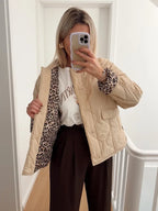 Close-up side view of the beige quilted jacket showing the leopard print lining revealed at the open front