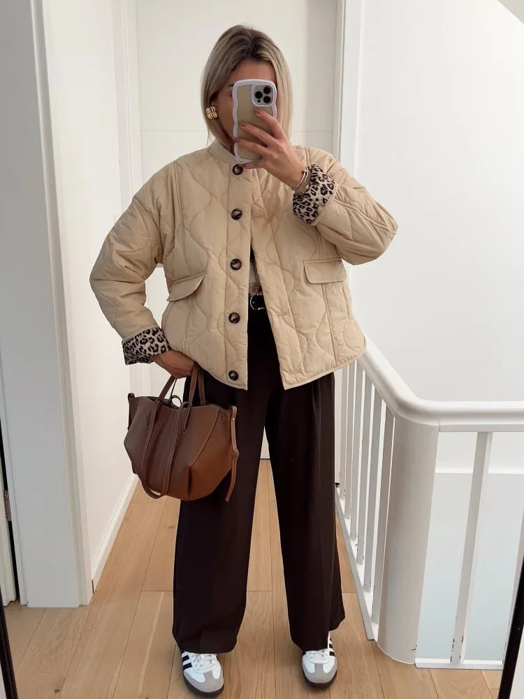 Beige quilted jacket styled with dark trousers and white trainers, shown with a tan handbag
