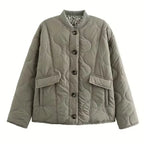 Flat lay of a sage green quilted jacket with dark buttons and a glimpse of the leopard print inner lining