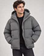 Man wearing a grey hooded puffer jacket, unzipped, over a black ribbed jumper and dark jeans