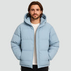 Front view of a man in a light blue hooded puffer jacket worn open over a white t-shirt