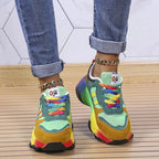 Back view of green and mustard chunky trainers worn with cuffed jeans, showing heel construction and sole