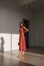 Side profile view of the red floral midi dress showing the gathered tie-front bodice and flowing skirt