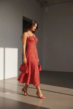 Woman walking outdoors in the red floral midi dress, holding a red handbag, showing the dress in motion