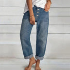 Front view of button-fly denim jeans in mid-blue wash, showing turned-up cuffs and relaxed leg silhouette